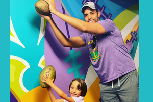 Father and daughter both catching gold footballs with colorful background. 