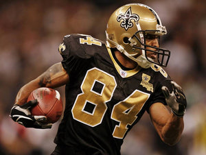 Michael Lewis in black & gold Saints football uniform and gold helmet mid-game carrying the football with a crowd behind him.