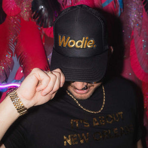 Black trucker hat with a applique that says Wodie. in gold