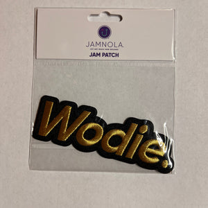 Gold and black 'Wodie' patch on a clear card with visible brand name.