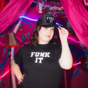 Person wearing a matchingblack t-shirt and trucker hat with 'FUNK IT' text in a colorful, neon-lit room.
