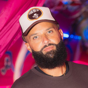 Man wearing a cap that says Funk Me Up with a blurred colorful background.