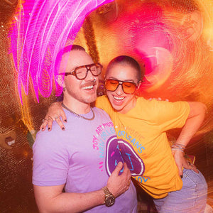 Two people posing together at JAMNOLA on Frenchmen with colorful light effects in the background.