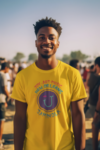 Man outside with other people in the background wearing a golden yellow short sleeve t shirt with the Jamnola logo in the center with the words "Joy Art Music New Orleans JAMNOLA" surrounding the puple logo.