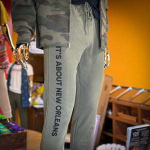 Olive  sweatpants with It's About New Orleans in black letters down the right leg