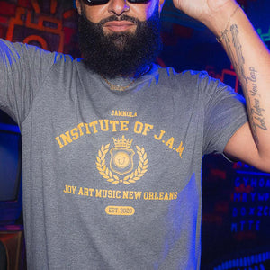 Man wearing a gray t-shirt with 'Institute of J.A.M' design, standing in a colorful indoor setting.