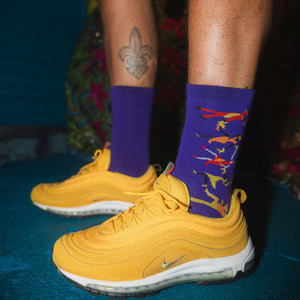 Yellow sneakers with purple socks featuring people dancing on a blue surface.