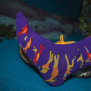 Purple novelty sock with colorful people in a second line on a blue surface
