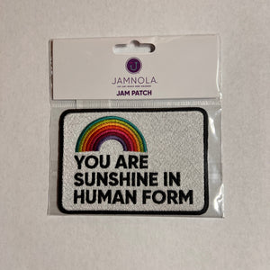 Embroidered patch with rainbow and text on a white card with JAMNOLA branding.