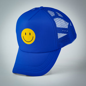 Bright blue trucker hat with a yellow smiley face tipped forward balancing on it's bill.