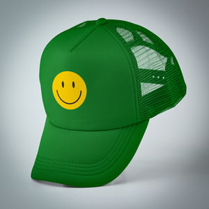 Bright green youth trucker hat with a yellow smiley face on the front balancing on it's bill.